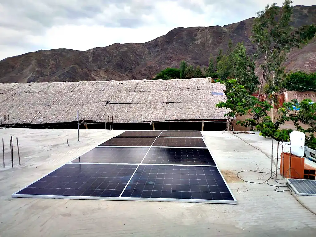 Instalación de paneles solares terminada por Compra Solar sobre techo, con palmera de carrizo y cerros de Ica al fondo