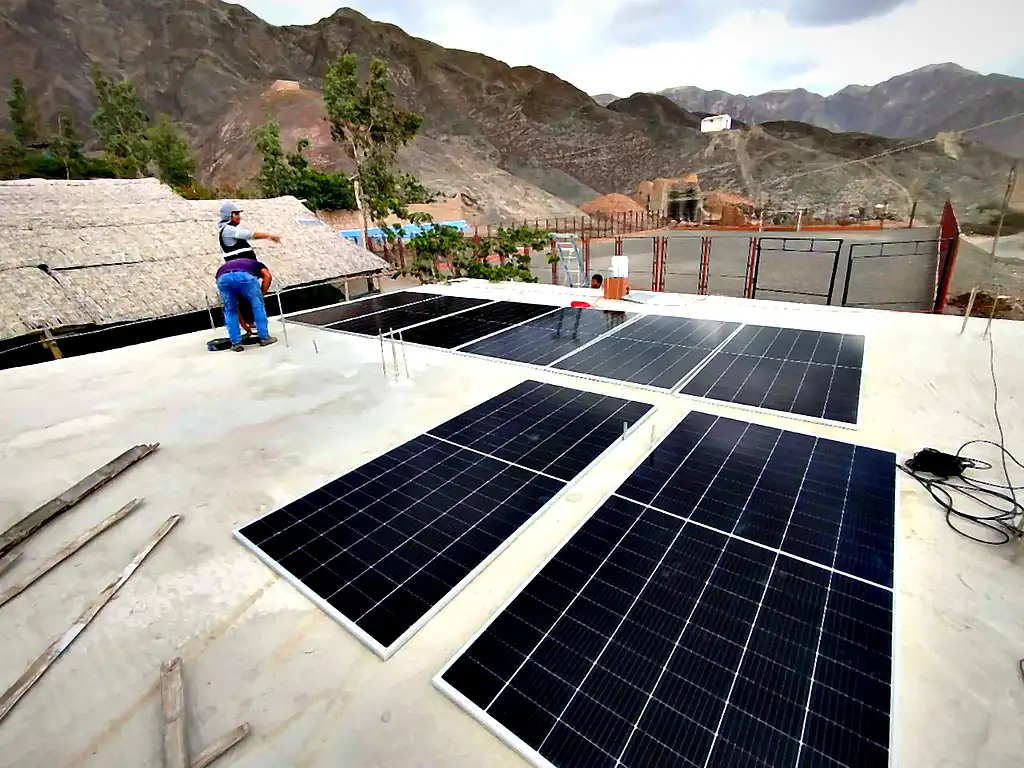 Técnico de Compra Solar instalando paneles solares sobre el techo de una vivienda en Ica, con los cerros áridos al fondo